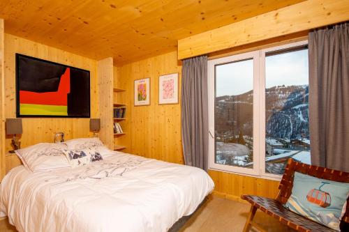 ein Schlafzimmer mit einem Bett und einem großen Fenster in der Unterkunft Chalet Gemme - Magnifique chalet piscine sauna in Saint-Étienne-de-Tinée
