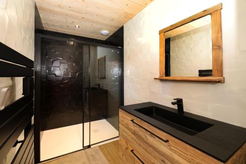une salle de bain avec un lavabo noir et un miroir dans l'établissement Chalet l'URSUS - séjour premium avec vue montagne, à Gérardmer