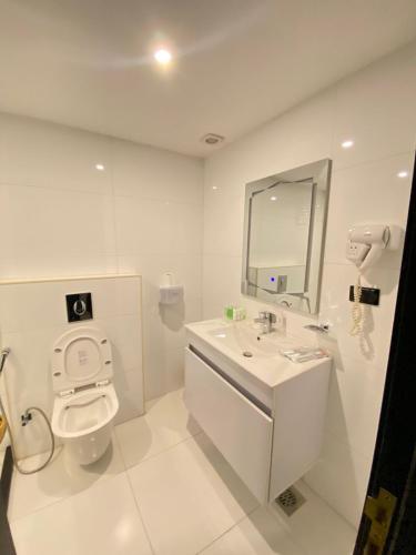 a white bathroom with a toilet and a sink at The RN Hotels in Wadi Musa