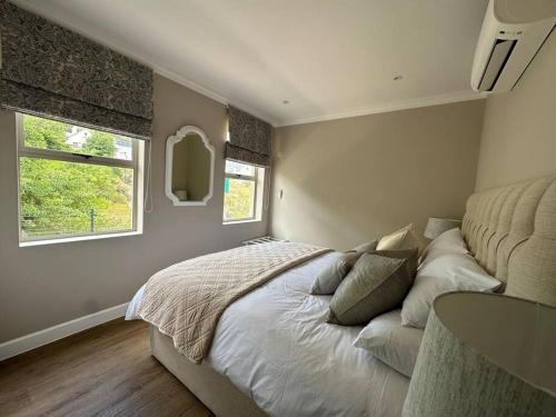 a bedroom with a large bed and two windows at Mountain View 1-Bedroom Villa in Franschhoek in Franschhoek