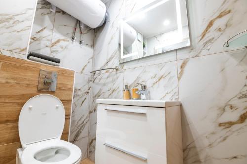 a bathroom with a white toilet and a sink at Apartmenthaus Oborishte in Panagyurishte