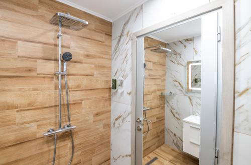 a shower in a bathroom with wooden walls at Apartmenthaus Oborishte in Panagyurishte