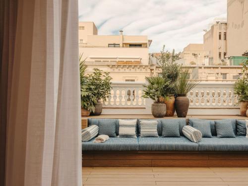 a blue couch on a balcony with plants at Hotel Pulitzer Barcelona in Barcelona