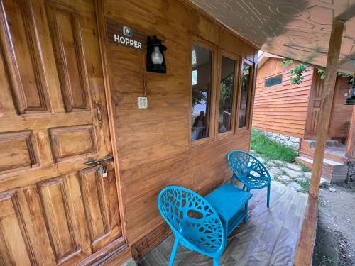a porch with two blue chairs and a door at Destination Lodges Camp Leo Hoppar Valley in Gilgit