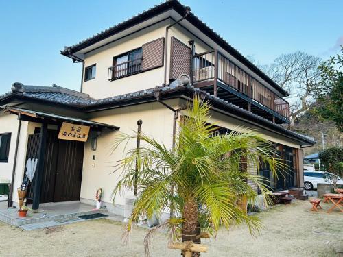 una casa con una palmera delante de ella en Guest House Uminokyojyusya - Vacation STAY 83084v, en Miyazaki