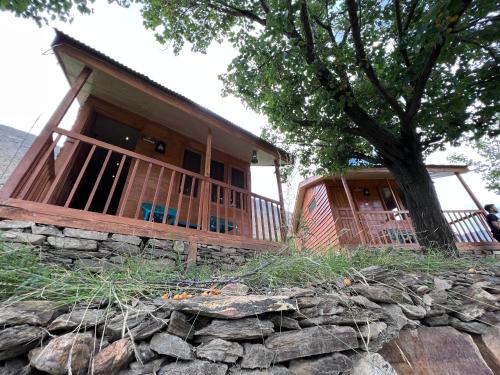 a house with a stone wall and a tree at Destination Lodges Camp Leo Hoppar Valley in Gilgit