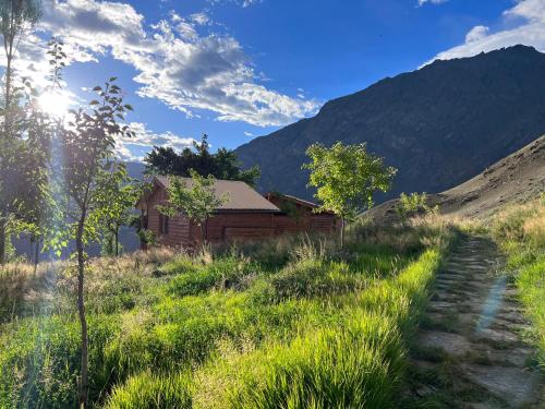 a house in a field with a path leading to it at Destination Lodges Camp Leo Hoppar Valley in Gilgit