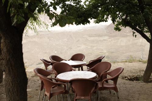 a row of tables and chairs under a tree at Destination Lodges Camp Leo Hoppar Valley in Gilgit