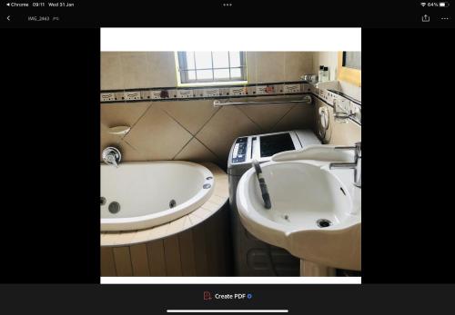 a bathroom with two sinks and a bath tub at Jimmyluh Self Catering in Durban