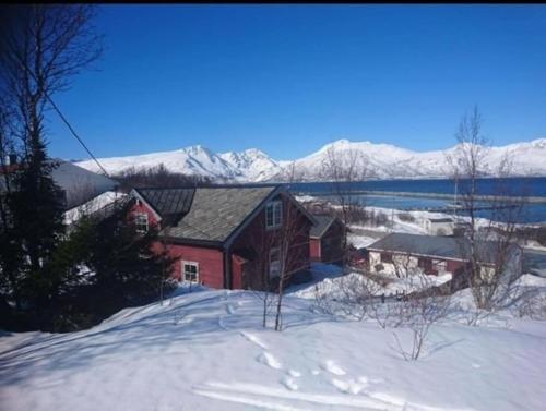 ein rotes Haus im Schnee mit Bergen im Hintergrund in der Unterkunft Det røde huset på Vågnes in Krokelvdalen