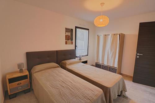 1 dormitorio con 2 camas y ventana en Appartement Le Frassu PORTICCIO en Porticcio