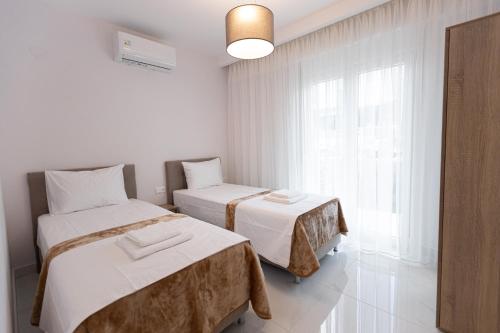 a white room with two beds and a window at Victoria Residence in Thessaloniki