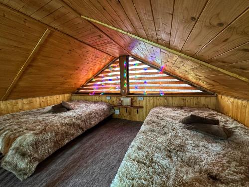 Duas camas num quarto com uma janela em Căsuța din Stejari-Transalpina em Novaci-Străini