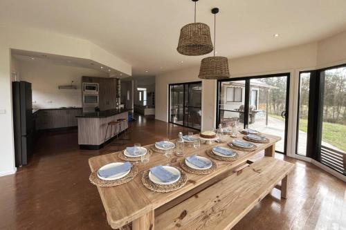 a wooden table with plates and glasses on it in a living room at The Ranch - Coastal Farmhouse midway to Newcastle Airport and Beaches in Salt Ash