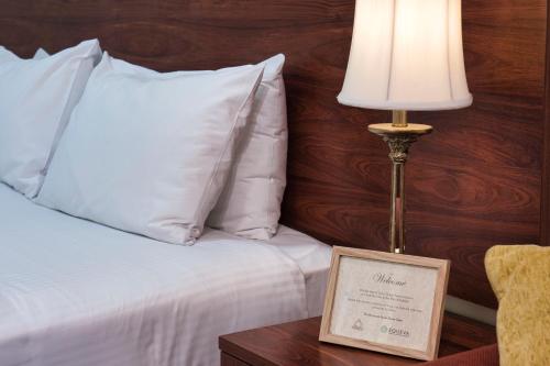 uma cama com almofadas brancas e um candeeiro sobre uma mesa em The Metropole Guest House Katoomba em Katoomba