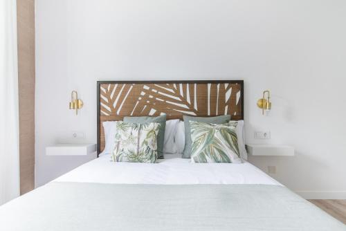 um quarto com uma cama branca com almofadas em Home2Book Stylish Apt Terrace & BBQ, Maspalomas em Maspalomas