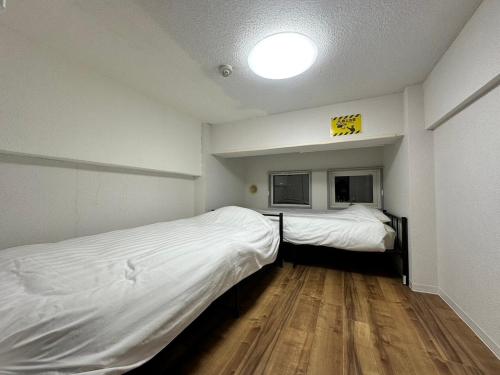 two beds in a small room with wood floors at 【NEW OPEN】AMS Hiragishi 402 in Sapporo