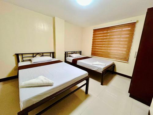 two beds in a room with a window at OYO 1045 Rayjan Apartelle in Manila