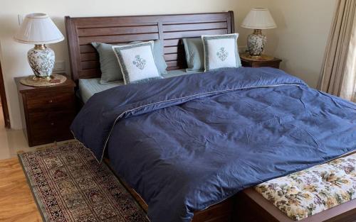 a bed with a blue comforter and two night stands at Vilasa by StayApart x Merlot Pines in Kasauli