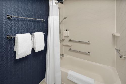 y baño con ducha, bañera y toallas. en Fairfield Inn & Suites Portland West Beaverton, en Beaverton