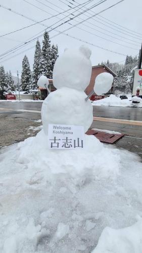 a snowman is sitting on the side of a street at Minsyuku Koshiyama in Shirakawa