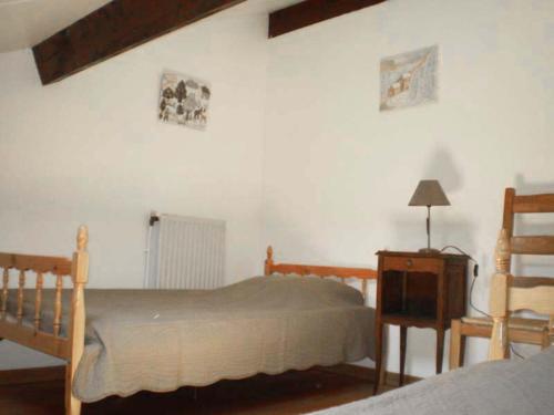 een slaapkamer met 2 bedden en een tafel met een lamp bij Les Sources Gîte La Grange in Chambonas