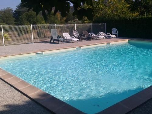 een groot zwembad met stoelen bij Les Sources Gîte La Grange in Chambonas