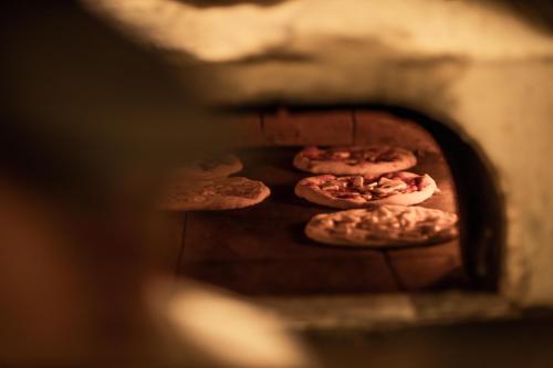 four pizzas are cooking in a pizza oven at Hotel & Ristorante Bellora in Gothenburg