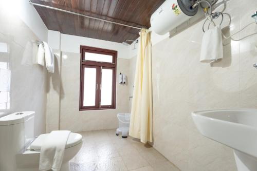 a white bathroom with a sink and a toilet at Summit Sherpa Mountain Hotel & Spa in Kalimpong