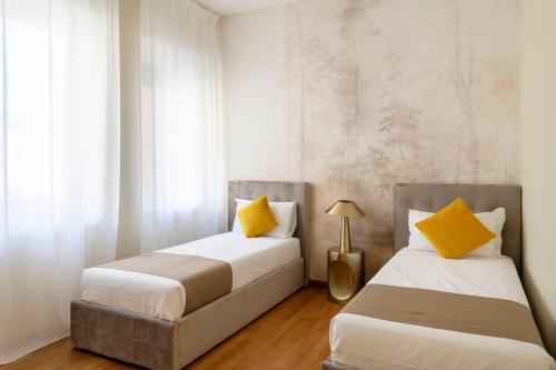 two beds in a room with white and yellow pillows at Heart Milan Apartments San Sepolcro Duomo in Milan