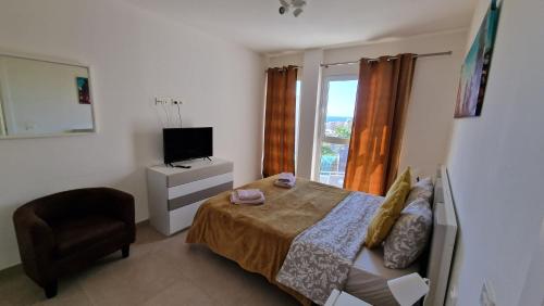 a bedroom with a bed and a chair and a television at Villa Paraiso-Luxury Villa with Heated Pool in Adeje