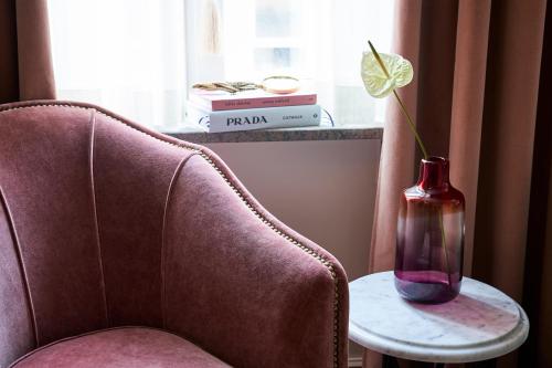 a vase on a table next to a chair with a flower in it at MJ's in Malmö
