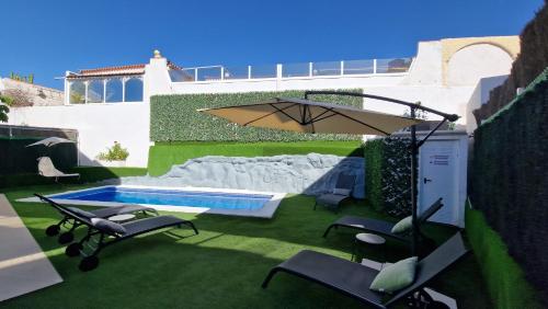 a patio with chairs and an umbrella and a pool at Villa Paraiso-Luxury Villa with Heated Pool in Adeje