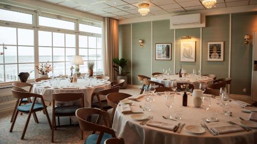 a dining room with tables and chairs and large windows at Falkenberg Strandbad in Falkenberg