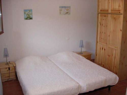 um quarto com uma cama branca e um armário de madeira em Les Sources Gite Cabernet em Chambonas