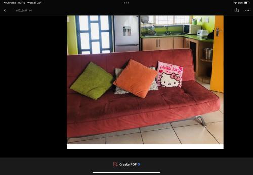 a red couch with pillows on it in a kitchen at JimmyLuh Garden Cottage in Durban