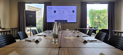 a large table in a room with chairs and a large screen at Kyriad Prestige - Bordeaux Aeroport in Mérignac