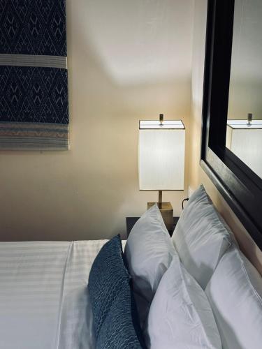 a bedroom with a bed with two pillows and a lamp at Parasol Blanc in Luang Prabang