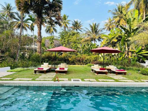 a pool with chairs and umbrellas next to a resort at Parasol Blanc in Luang Prabang
