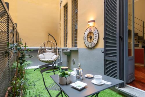 a small patio with a table and a clock on a building at Heart Milan Apartments San Sepolcro Duomo in Milan