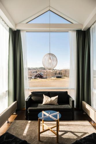 a living room with a black couch and a large window at Sundvolden Hotel in Sundvollen