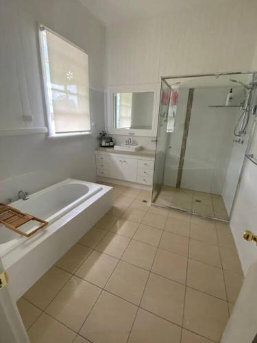 a white bathroom with a tub and a shower at The Sugarloaf Homestead in Kyoomba