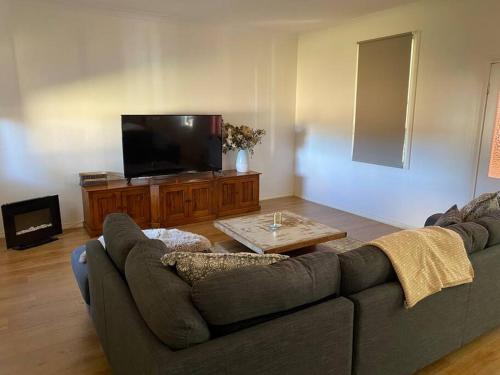 a living room with a couch and a flat screen tv at The Sugarloaf Homestead in Kyoomba