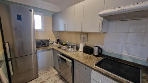 a kitchen with white cabinets and a stainless steel refrigerator at Residencial Benimar Licencia Vv in Adeje