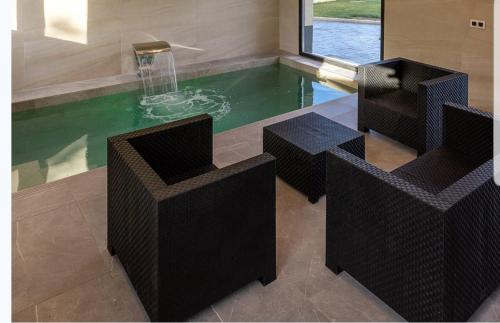 a swimming pool with chairs and a fountain at Las vistas del valle in Hontoba