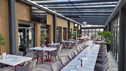 a restaurant with white tables and chairs and windows at Baumberger Rheinterrassen in Baumberg