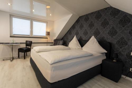 1 dormitorio con 1 cama con sábanas blancas y mesa en Baumberger Rheinterrassen, en Baumberg