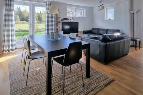 een woonkamer met een tafel en stoelen en een bank bij Stuga Fyra Säsonger - Fishing - Skiing - Hottub in Filipstad