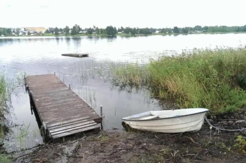a boat on the shore of a lake with a dock at Stuga Fyra Säsonger - Fishing - Skiing - Hottub in Filipstad