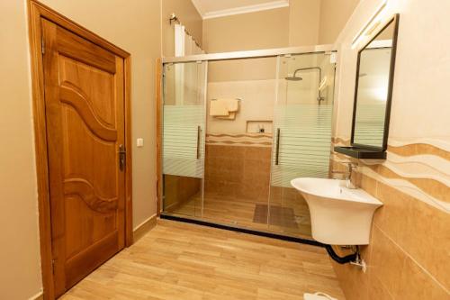 uma casa de banho com uma cabina de duche em vidro e um lavatório. em INGANZO BOUTIQUE HOTEL em Kigali